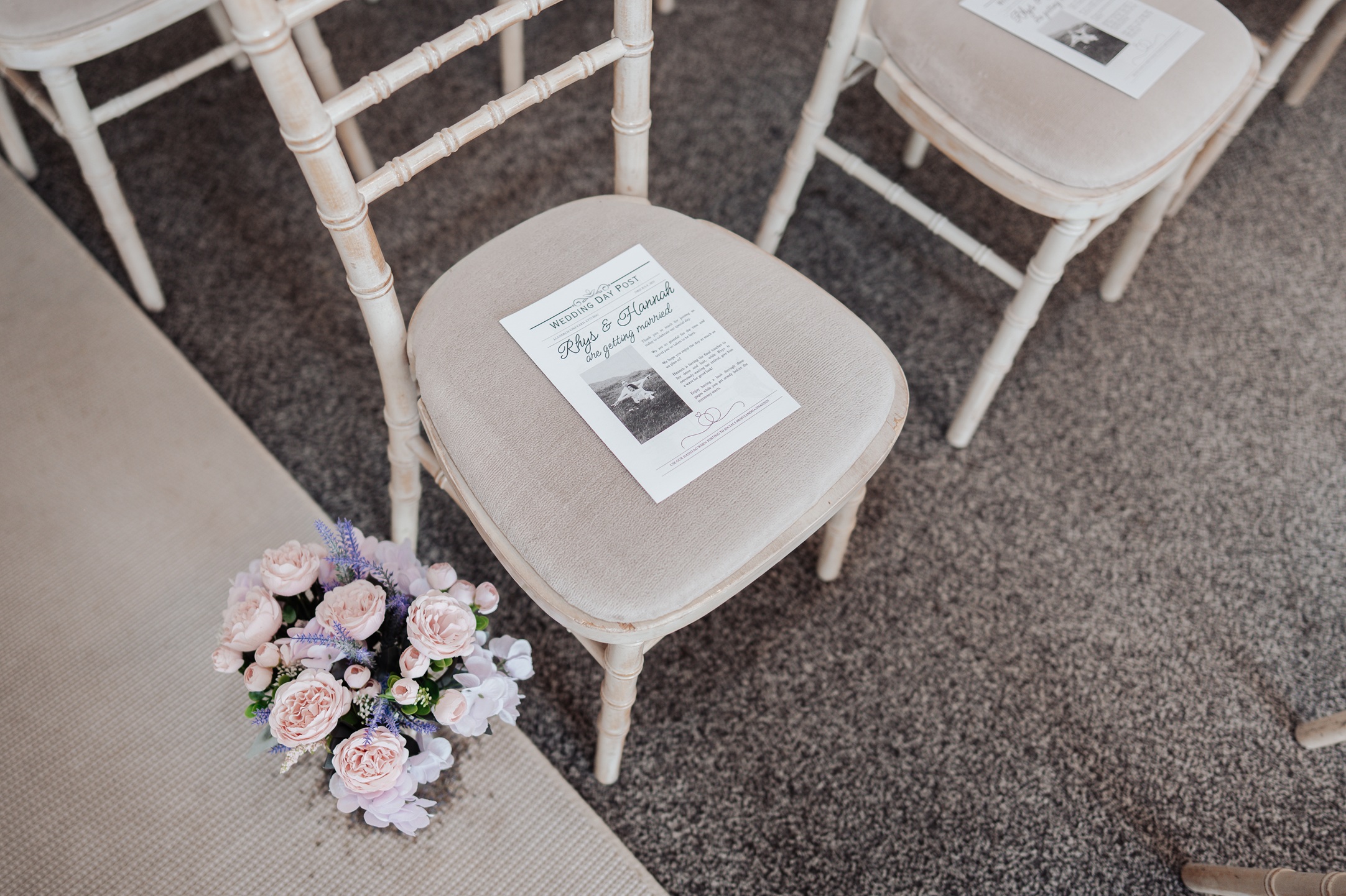 A close-up of a wedding invitation or program placed on a chair, with a small floral bouquet on the floor next to it. 
                        The chairs are arranged for a wedding ceremony.