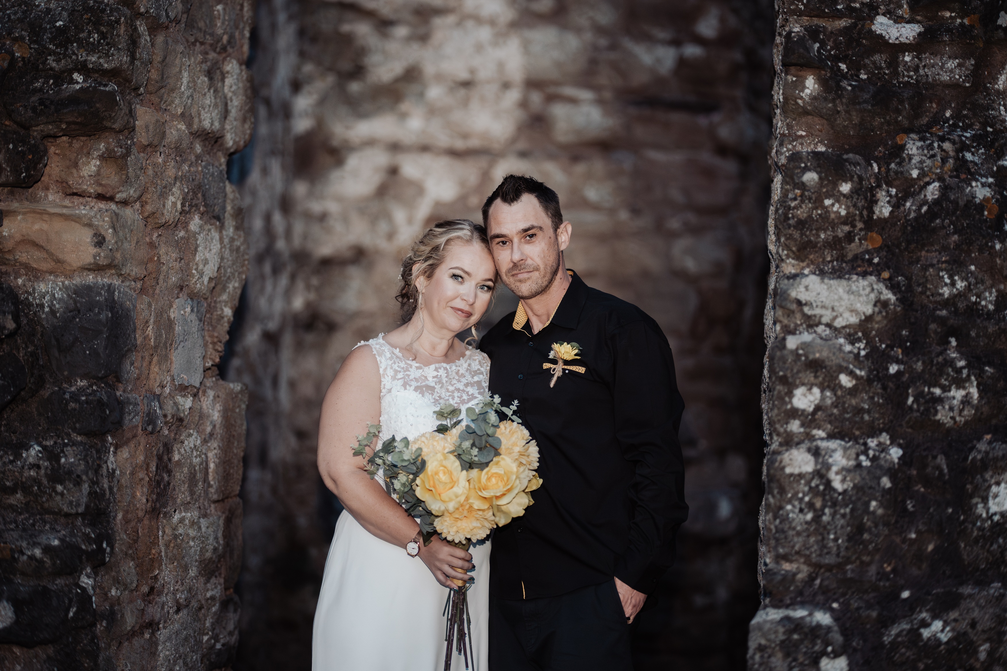 A newly wed couple stands in a stone doorway at Caldicot Castle.