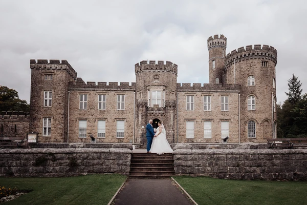 A couple stands on the steps in front of Cyfarthfa Castle.