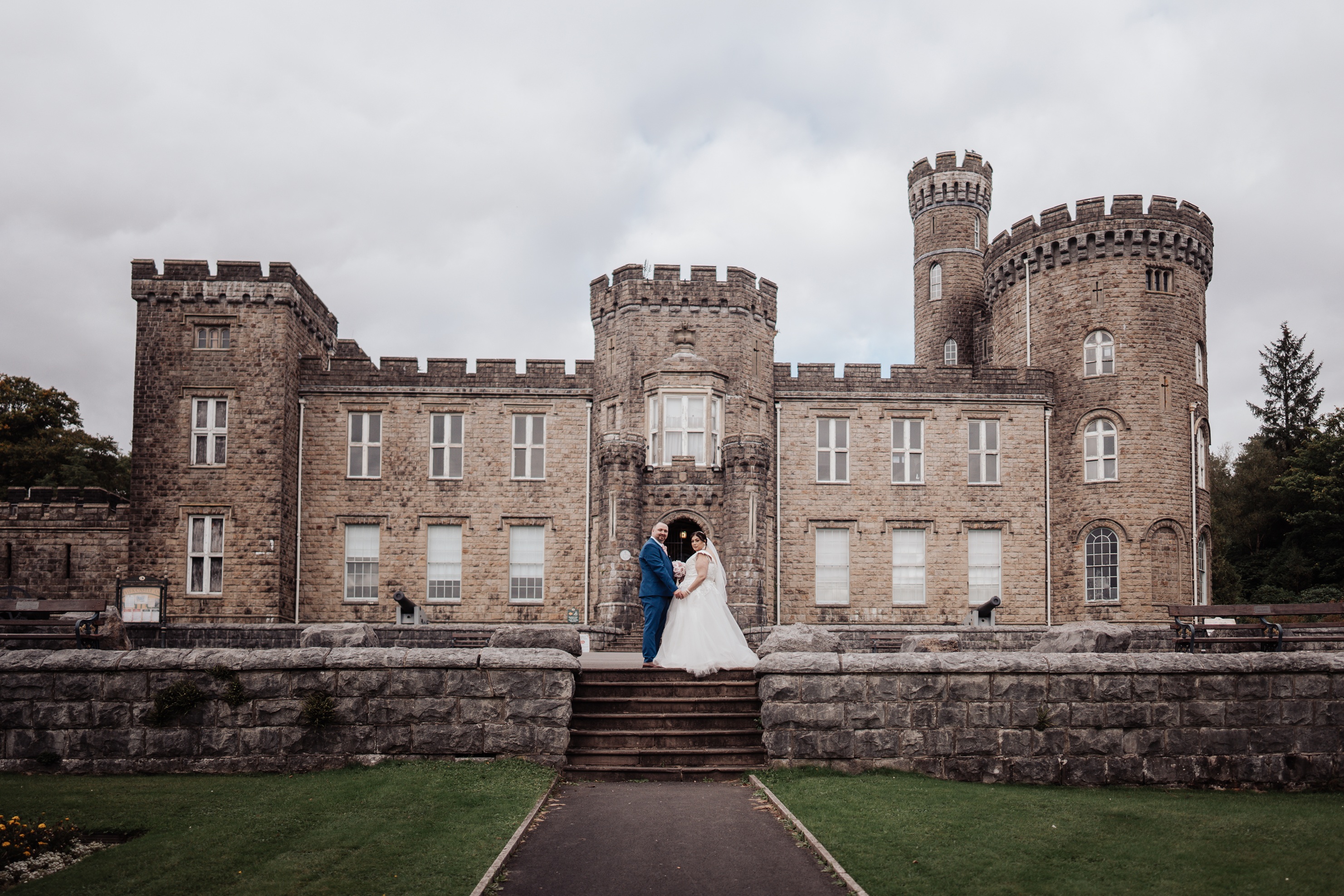 A couple stands on the steps in front of Cyfarthfa Castle.