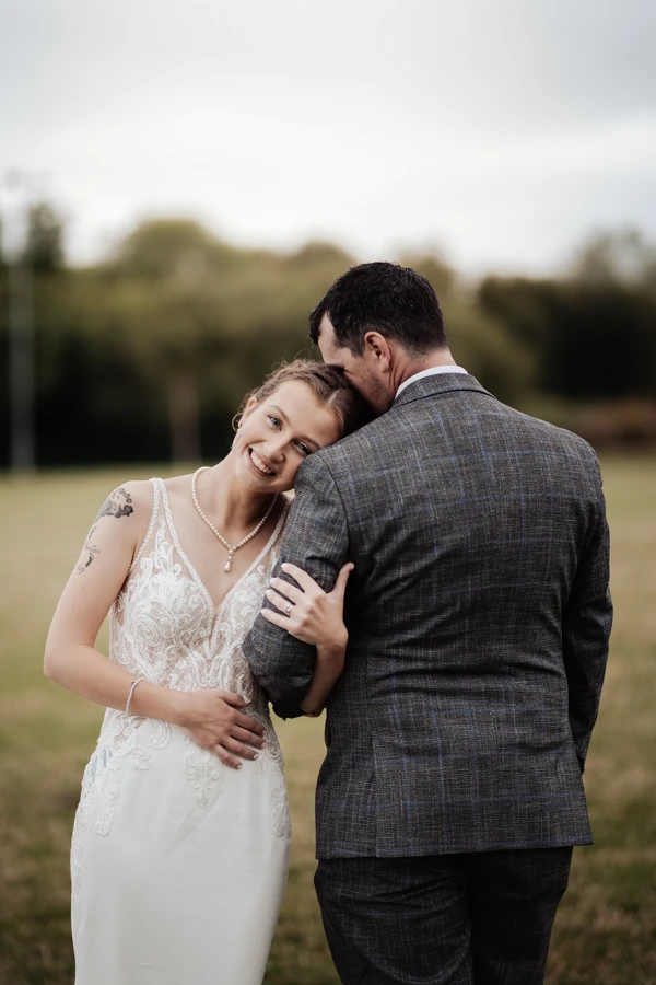Bride and groom embracing in a field in Taunton.